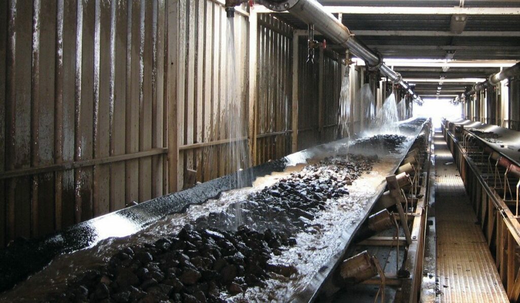 Interior view of a wet belt. You can see the aggregates being sprinkled with cold water on the conveyor belt.