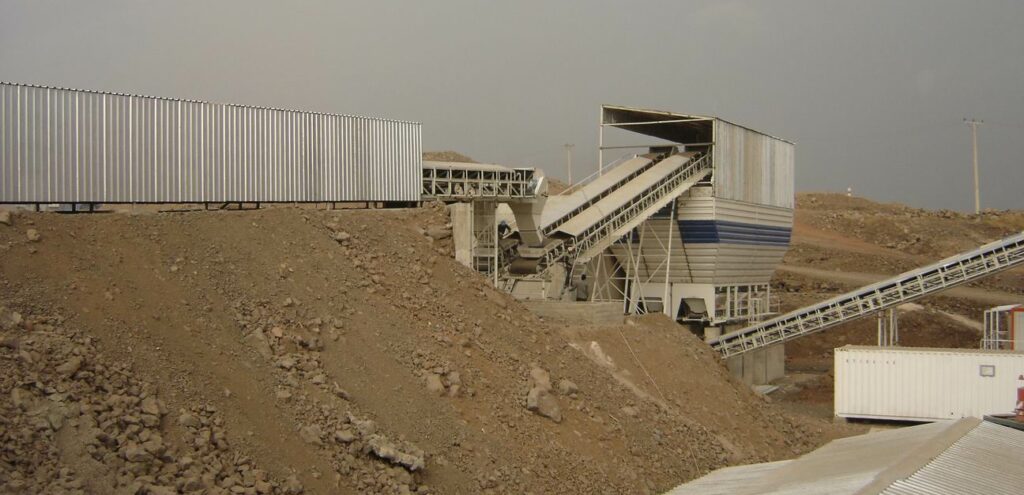 Construction of an aggregate cooling system with so-called wet belts in front of the row dosing unit. The water flows against the aggregate flow on the wet belts. This generates a high cooling rate.